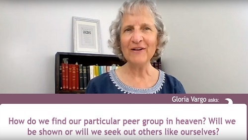 Karin sits at her desk in front of a bookshelf. A question from audience member Gloria Vargo appears across the bottom of the screen, reading: "How do we find our particular peer group in heaven? Will we be shown or will be seek out others like ourselves?"