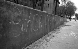 A black and white photograph of the words "Black Lives Matter" written on a concrete wall.